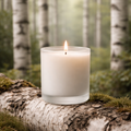 Birch scented candle. frosted glass tumbler sitting on a birch stump surrounded by birch branches 