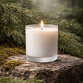 Candle in a glass container on a stone surface with a forest background. Hinoki tree scented candle